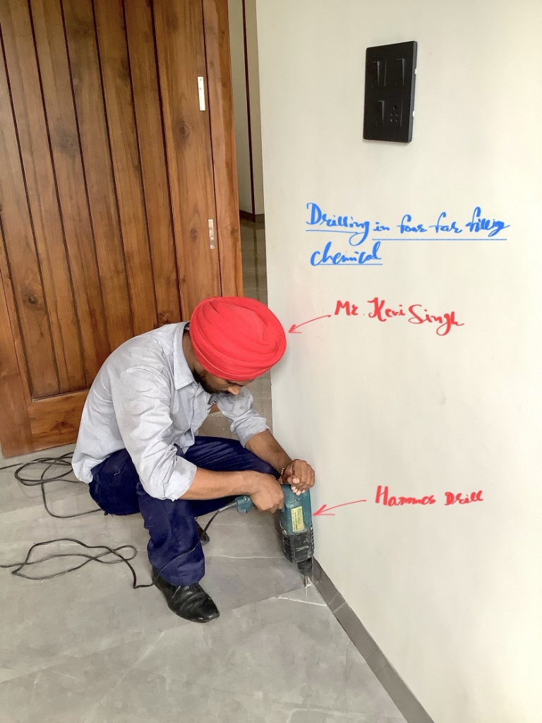 OPC technician drilling beside a door frame for termite treatment